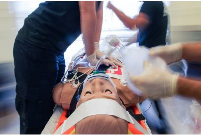 HAL patient simulator on stretcher while learners perform chest compressions