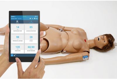 Susie Simon Nursing Care Patient Simulator lying down; an instructor programs healthy vital signs with the OMNI2.